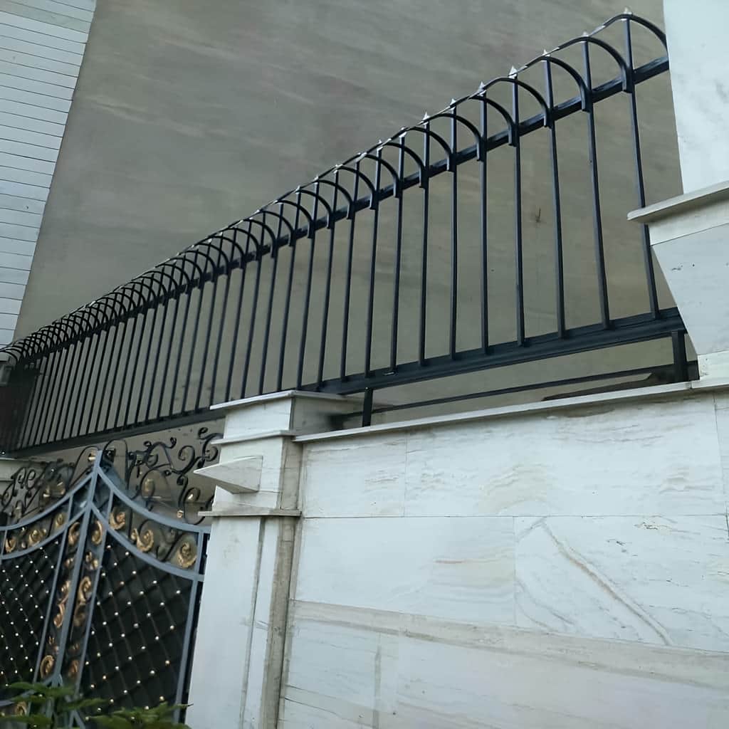 نصب حفاظ سرنیزه ای روی دیوار سنگی حیاط