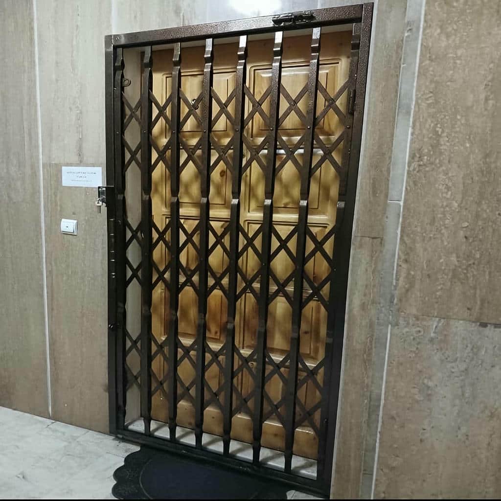 حفاظ درب آکاردئونی سفید پشت درب اصلی چوبی