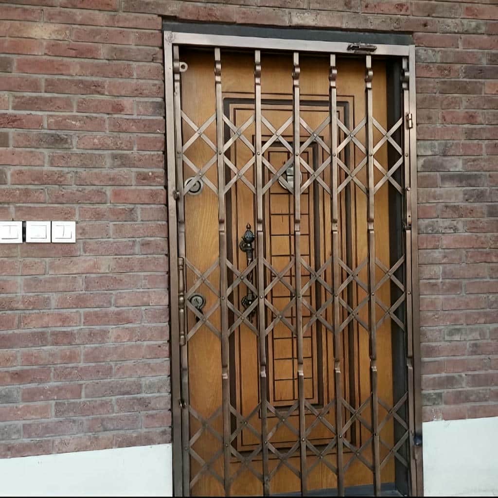 حفاظ درب آکاردئونی مشکی کنار چهارچوب قدیمی زاهدان