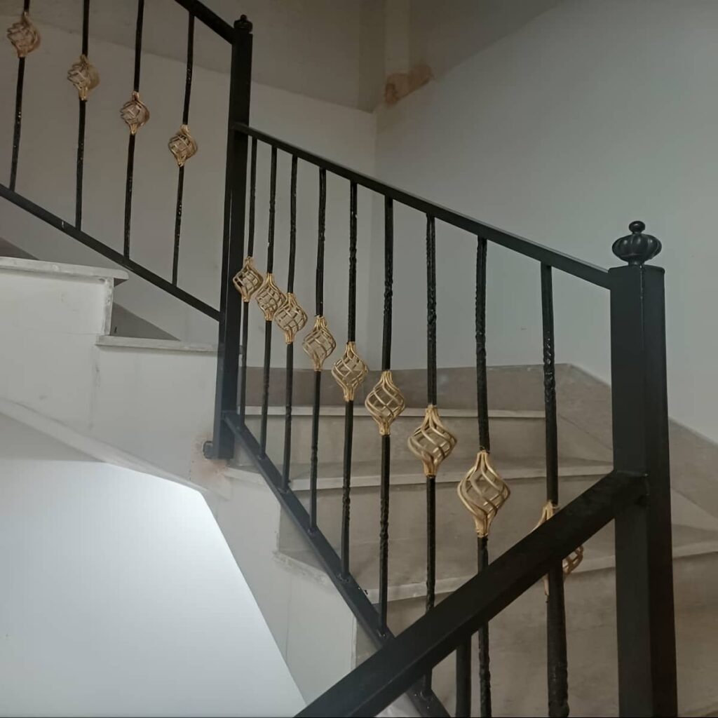 نرده راه پله سفید کنار دیوار سنگی ساختمان