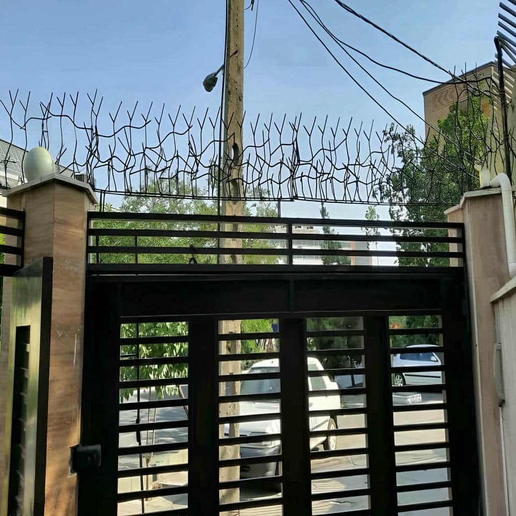 نرده سرنیزه‌ای خاکستری کنار دروازه ویلایی