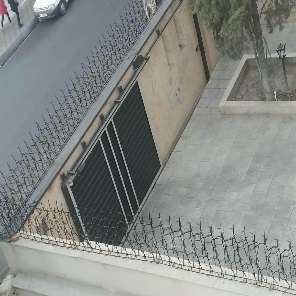 گارد فلزی طوسی روی دیوار سفید حیاط